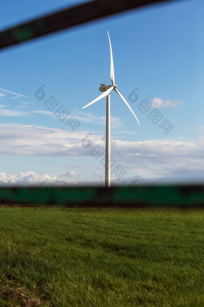 风车与新鲜的绿色草和清晰的蓝色的天空夏天能源概念附近栅栏风车与新鲜的绿色草和清晰的蓝色的天空夏天能源概念附近栅栏