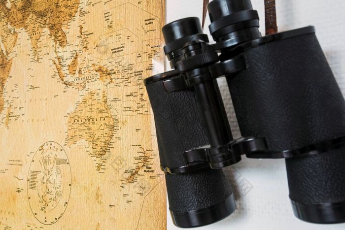 黑色的双筒望远镜和地图挂白色墙旅行概念特写镜头黑色的双筒望远镜和地图挂白色墙旅行概念