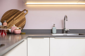 特写镜头计数器和现代厨房钢水槽与粉红色的墙和装饰现代光室内清洁特写镜头计数器和现代厨房钢水槽与粉红色的墙和装饰现代光室内