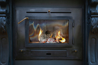 传统黑色的木燃烧炉子特写镜头与火火焰古董设计舒适的室内传统黑色的木燃烧炉子特写镜头与火火焰古董设计舒适的