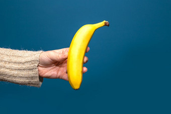 手持有黄色的香蕉水果孤立的蓝色的背景手持有黄色的香蕉水果孤立的附近蓝色的背景