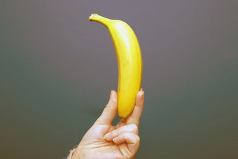 手持有黄色的香蕉水果孤立的色彩斑斓的背景手持有黄色的香蕉水果附近色彩斑斓的背景