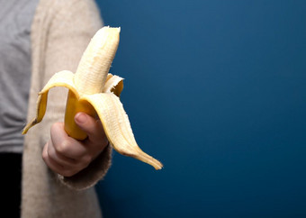 人持有黄色的香蕉水果手附近蓝色的背景给走了健康的概念特写镜头人持有黄色的香蕉水果手附近蓝色的背景给走了健康的概念