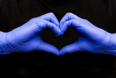 蓝色的乳胶手套为医疗保护心形式象征支持的医生和护士新冠病毒冠状病毒红色的背景黑色的背景蓝色的乳胶手套为医疗保护心形式象征支持的医生和护士新冠病毒冠状病毒黑色的背景