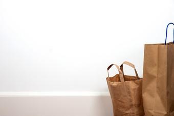 关闭棕色（的）购物袋对白色墙木地板上复古的设计空间为文本特写镜头关闭棕色（的）购物袋对白色墙木地板上复古的设计空间为文本
