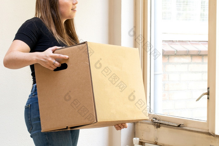 快乐年轻的女人携带纸板移动盒子为她的新首页移动新房子概念脆弱的和复古的快乐年轻的女人携带纸板移动盒子为她的新首页移动新房子概念