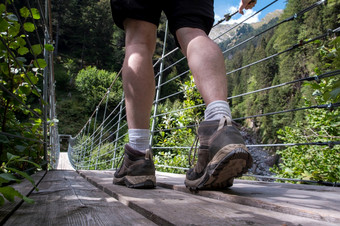 一个人年轻的男人。走悬架桥瑞士徒步旅行与美丽的景观旅行一个人年轻的男人。走悬架桥瑞士徒步旅行与美丽的景观