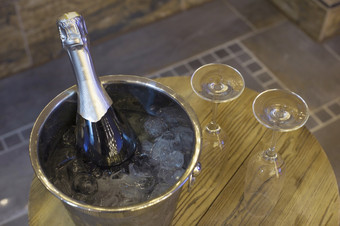 香槟瓶冷却器桶与冰和两个香槟眼镜木表格浪漫的晚餐和聚会，派对概念特写镜头香槟瓶冷却器桶与冰和两个香槟眼镜木表格浪漫的晚餐和聚会，派对概念