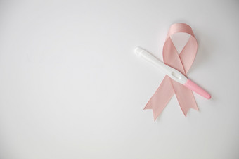粉红色的缎乳房癌症意识丝带与空白怀孕测试孤立的白色背景前视图空间为文本粉红色的缎乳房癌症意识丝带与空白怀孕测试孤立的白色背景前视图