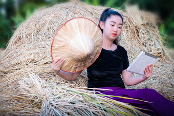 肖像女人农民使用数字平板电脑而坐着帕迪场的稻草背景农村场景泰国