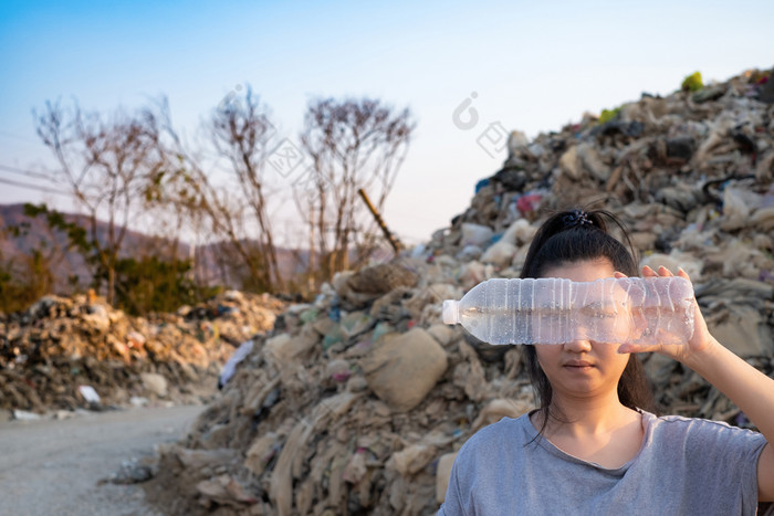 女人手持有使用清晰的塑料瓶封面的脸山大垃圾背景这些浪费来从城市和工业区域可以不得到掉桩臭和有毒残留