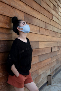 关闭年轻的亚洲女人把医疗面具保护从机载呼吸疾病的流感新冠病毒灰尘和烟雾墙老木背景