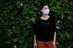 肖像年轻的亚洲女人站和把时尚面具叶墙背景与复制空间