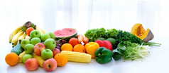 各种各样的新鲜的成熟的水果和蔬菜的表格白色窗帘背景食物概念背景