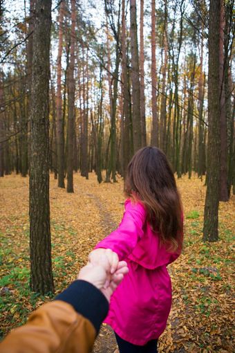 女孩粉红色的雨衣持有她的的男朋友rsquo手的秋天森林女孩粉红色的雨衣持有她的的男朋友rsquo手的秋天森林