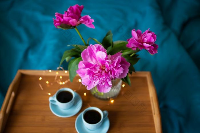 美丽的粉红色的牡丹和两个杯咖啡是站木托盘床上特写镜头视图从以上美丽的粉红色的牡丹和两个杯咖啡是站木托盘床上特写镜头视图从以上