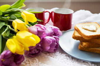 伟大的早餐两个杯咖啡烤面包与花生黄油和美丽的明亮的花束郁金香伟大的早餐两个杯咖啡烤面包与花生黄油和美丽的明亮的花束郁金香