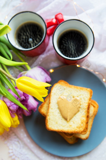 可爱的早餐床上黑色的咖啡明亮的花烤面包与花生黄油可爱的早餐床上黑色的咖啡明亮的花烤面包与花生黄油