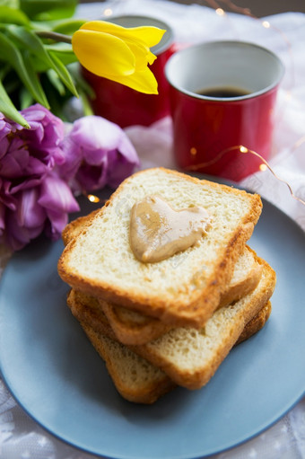 可爱的早餐床上黑色的咖啡明亮的花烤面包与花生黄油特写镜头可爱的早餐床上黑色的咖啡明亮的花烤面包与花生黄油特写镜头