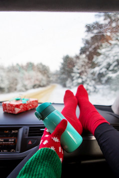的女孩持有热水瓶而坐着的车冬天的背景的冬天森林旅行旅行和冬天概念的女孩持有热水瓶而坐着的车冬天的背景的冬天森林旅行旅行和冬天概念