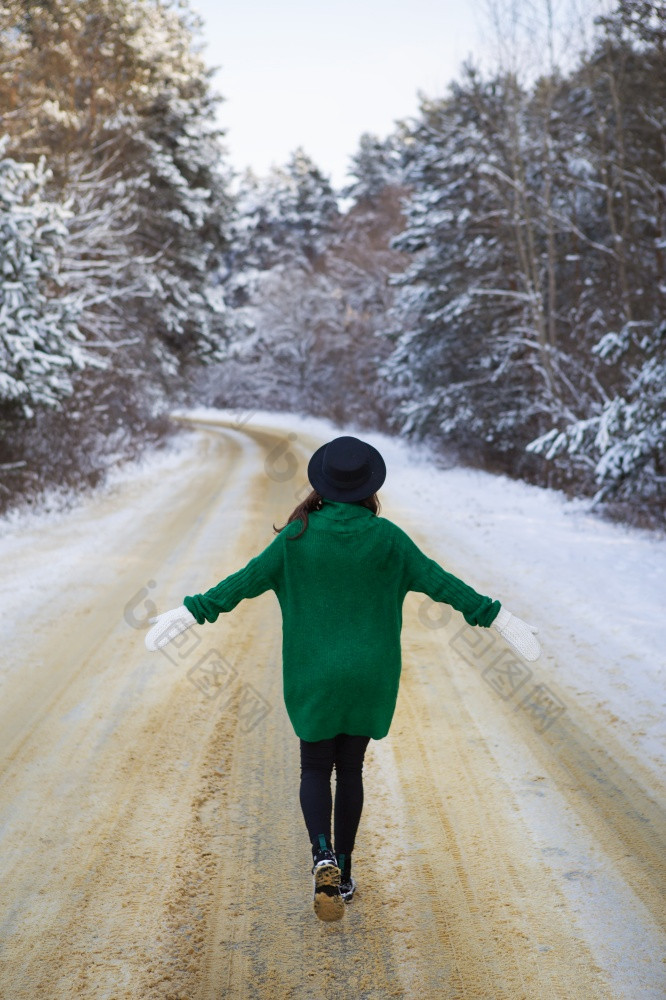 年轻的女孩绿色毛衣和他走的中间雪路厚松森林冻结一天年轻的女孩绿色毛衣和他走的中间雪路厚松森林冻结一天