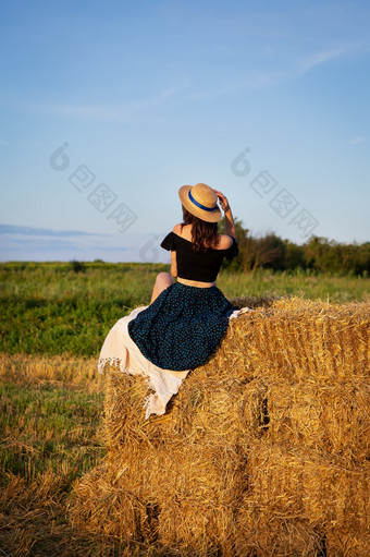 年轻的美丽的女人稻草他看起来的设置太阳的女孩坐在大桩稻草包温暖的夏天晚上年轻的美丽的女人稻草他看起来的设置太阳的女孩坐在大桩稻草包温暖的夏天晚上