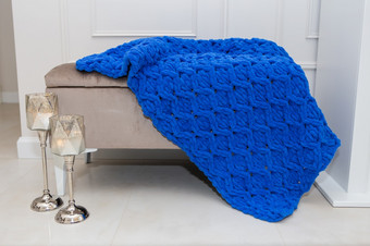 特写镜头美丽的蓝色的针织豪华的羊毛毯子休息的沙发沿着与<strong>烛台</strong>温暖的和舒适的概念特写镜头美丽的蓝色的针织豪华的羊毛毯子休息的沙发沿着与<strong>烛台</strong>温暖的和舒适的概念