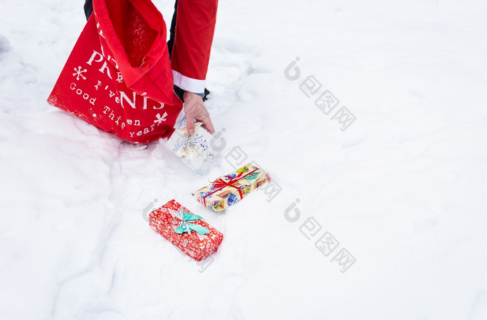 男人。穿着圣诞老人老人收集礼物雪森林的雪色彩斑斓的盒子与礼物男人。穿着圣诞老人老人收集礼物雪森林的雪色彩斑斓的盒子与礼物