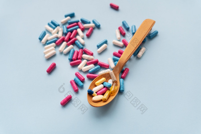各种各样的药片蓝色的背景在一起与木勺子哪一个维生素各种各样的药片蓝色的背景在一起与木勺子哪一个维生素