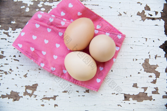 鸡蛋粉红色的桌布在老易破的白色木背景前视图鸡蛋桌布在木背景