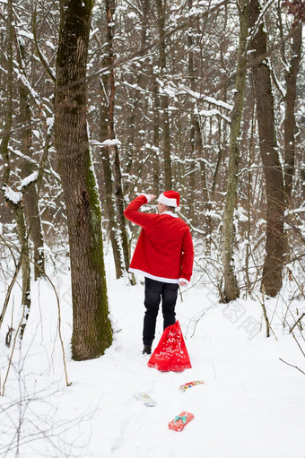 传统的圣诞老人老人他和袋礼物走通过的森林和看起来成的距离回来视图传统的圣诞老人老人他和袋礼物走通过的森林和看起来成的距离回来视图