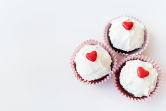 情人节,2月甜蜜的巧克力松饼与黄油奶油和红色的心为装饰白色背景情人节,2月甜蜜的巧克力松饼与黄油奶油和红色的心为装饰白色背景