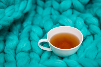 的概念安逸和安慰绿色针织毯子哪一个在那里白色杯热茶的地方为登记的概念安逸和安慰绿色针织毯子哪一个在那里白色杯热茶的地方为登记