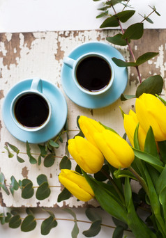 两个蓝色的杯咖啡与黄色的郁金香老表格特写镜头新鲜酿造咖啡