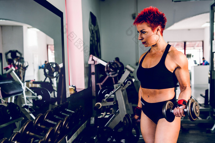 年轻的肌肉发达的强大的女人持有哑铃的健身房健身重量提升健身手臂肱二头肌培训