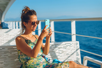年轻的女人的板凳上甲板的渡船船船<strong>游艇</strong>采取照片<strong>图片</strong>使用她的聪明的移动电话而航行的假期阳光明媚的一天