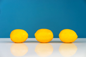 黄色的成熟的柠檬切片一半多汁的柑橘类水果的白色表格前面的蓝色的背景墙新鲜的水果