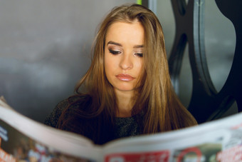 年轻的女孩女人坐着的咖啡馆餐厅首页持有和阅读报纸反应的文章新闻