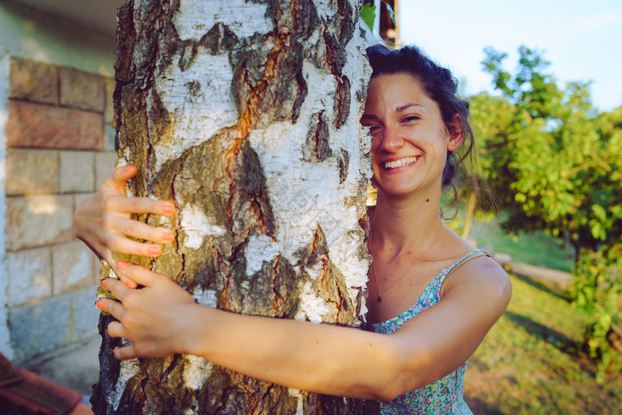 年轻的女人夏天衣服拥抱拥抱树树干她的后院图片