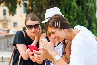 三个女人看的智能手机移动电话搜索为的<strong>旅游信息</strong>照片的科孚岛小镇