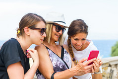 三个女人看的智能手机移动电话搜索为的旅游信息照片