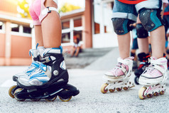 关闭孩子们rsquo腿穿辊叶片溜冰鞋学习骑的沥青的学校院子里活动
