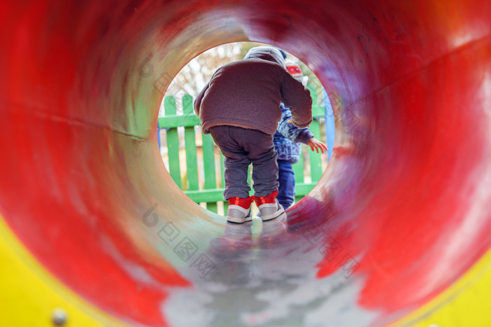 小高加索人男孩回来视图的公园的操场上的红色的隧道管穿冬天外套秋天一天有有趣的玩走
