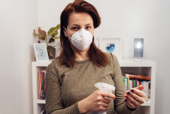 肖像成熟的高加索人女人穿抗菌保护面具在流感大流行站前面书架上工作首页防止疾病传播应用酒精消毒液手