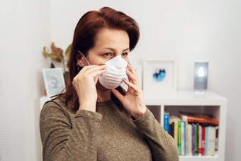 肖像成熟的高加索人女人调整杀毒抗菌保护面具在流感大流行而站前面的书架上工作首页防止疾病传播