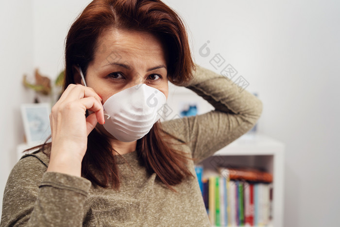 肖像成熟的高加索人女人穿杀毒抗菌保护面具在流感大流行而站前面的书架上工作首页防止疾病传播前面视图