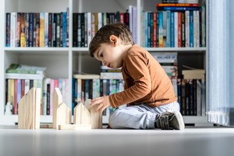 完整的长度视图小高加索人男孩小孩子首页孩子玩与木玩具砖形状房子坐着的木乙烯<strong>基层</strong>压地板上独自一人发展中创造力一边视图