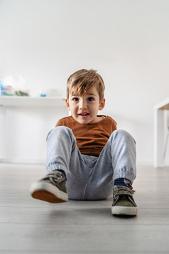 穿着小高加索人男孩可爱的小孩子孩子坐着的层压木乙烯基地板上首页一天独自一人微笑有有趣的好玩的