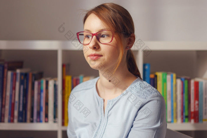 前面视图肖像美丽的年轻的成人高加索人女人女女孩坐着的椅子首页办公室前面的书架上看的一边穿眼镜衬衫一天