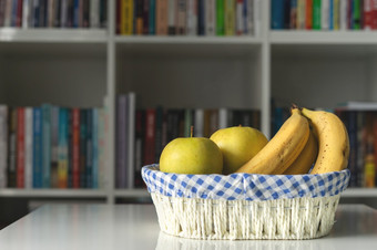成熟的水果香蕉和苹果白色篮子的表格前面的书架上首页办公室一天有机食物素食主义者素食者